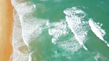 Aerial view of sand beach and water surface texture. Foamy waves with sky. Drone flying of beautiful tropical beach. Amazing Sandy coastline with white sea waves. Nature, seascape and summer concept. video