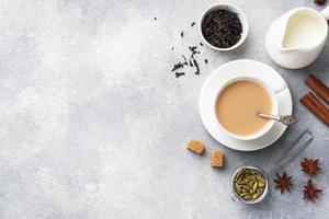 Indian drink masala tea with milk and spices. Cardamom sticks cinnamon star anise cane sugar. Concrete grey table copy space. photo