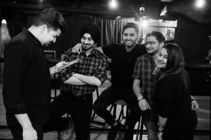 Group of indian friends sitting at lounge bar, having rest and look at menu. photo