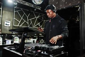 African american dj play music on decks at night club. photo