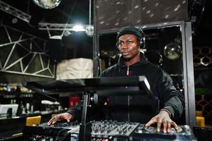 African american dj play music on decks at night club. photo