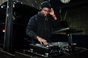 African american dj play music on decks at night club. photo