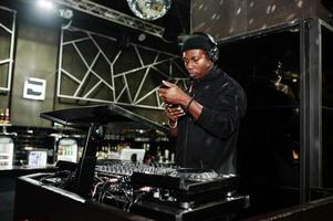 African american dj play music on decks at night club. photo