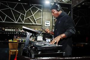 African american dj play music on decks at night club. photo