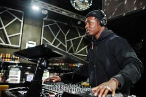 African american dj play music on decks at night club. photo