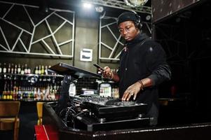 African american dj play music on decks at night club. photo