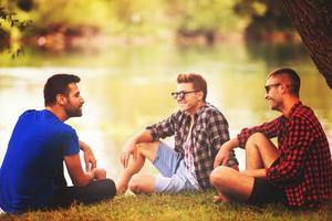 men sitting on the bank of the river photo