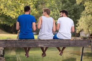 men enjoying watermelon while sitting on the wooden bridge photo