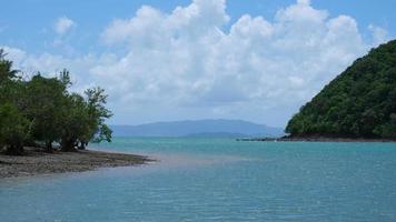 Beautiful sea waves and white sand beach in the tropical island. Ocean beach with soft waves and bright clouds in the sky on a hot summer day. Concept of relaxation and travel on vacation. video