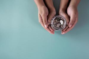 Adult and kid hands holding a coins jar savings and donation concept photo