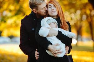 familia joven e hijo recién nacido en el parque de otoño foto