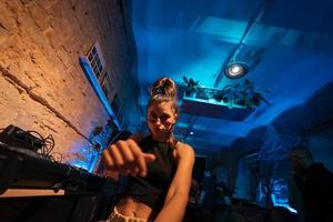 Beautiful female DJ dancing to techno in a small club photo