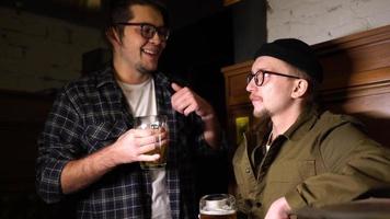 Young friends having fun together drinking beer and clinking glasses in a pub. photo