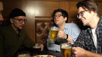 Young friends having fun together drinking beer and clinking glasses in a pub. photo