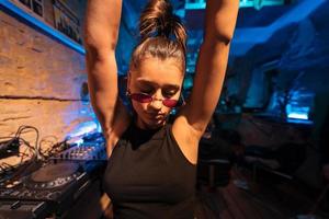 Beautiful female DJ dancing to techno in a small club photo