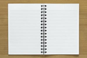 open spiral notebook on wood background photo