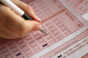 Filling out a lottery ticket. A young woman plays the lottery and dreams of winning the jackpot. Female hand marking number on red lottery ticket photo