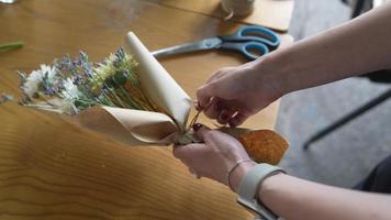 Florist wraps flower bouquet in brown paper and twine video