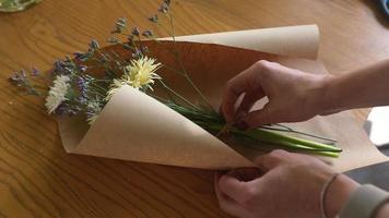 Florist wraps flower bouquet in brown paper and twine video