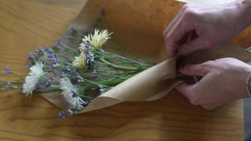 Florist wraps flower bouquet in brown paper and twine video