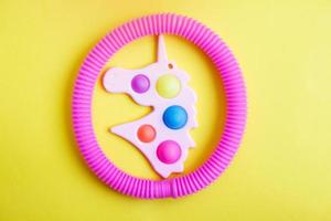 Simple dimple in the form of unicorn and a tube fidget toy on a yellow background photo