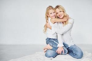 cercanía de la gente. madre con su hija juntas en el estudio con antecedentes blancos foto