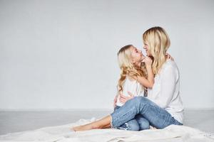 madre con su hija juntas está en el suelo en el estudio con antecedentes blancos foto