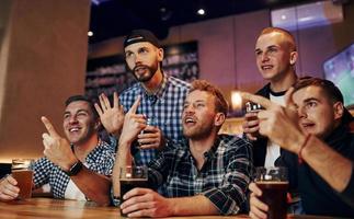 Football fans watching TV. Group of people together indoors in the pub have fun at weekend time photo