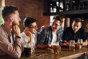 Positive friends. People in casual clothes sitting in the pub photo