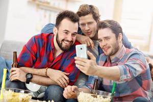 Happy male friends cheering and watching sports on tv photo