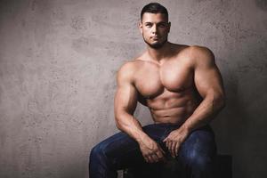 Massive bodybuilder posing beside the concrete wall photo