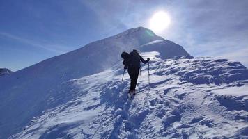 caminhante solo andando nas montanhas em um dia ensolarado muito ventoso. caminhada de inverno ao ar livre. viagem de inverno. aventura e explorar as montanhas. condições exigentes e difíceis para caminhadas de inverno. video