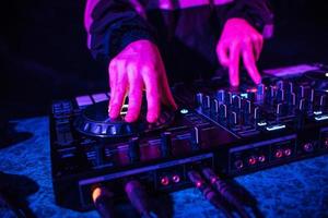 DJ console for mixing music with hands and with blurred people dancing at a night club party photo