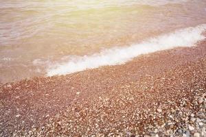 Bank of pebbles with the sea and beach in the background photo