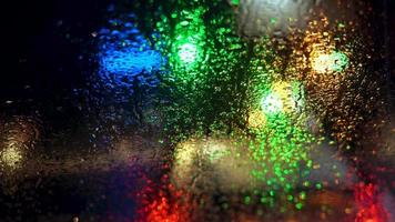 Close up rain drops on car window glass with blurred night city car lights bokeh as background video