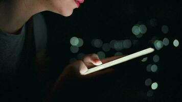 Woman is typing on a smartphone at night. Blurred lights in the background video