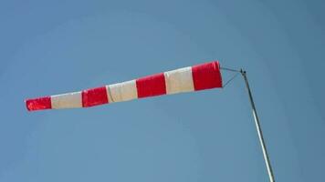 A red and white striped flag flying high in the clear blue sky video