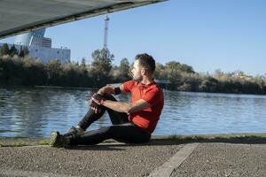 A closeup shot of a young male in sports costume sitting on the body of the river photo