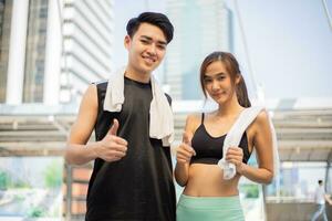 Sports man holding towel talking with fitness woman holding water outdoors. photo