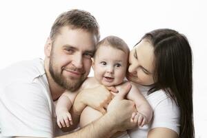 cerca arriba retrato de joven padres y bebé. padre y madre Beso y abrazo un hermosa pequeño hijo. el concepto de amar, contento paternidad y maternidad. foto