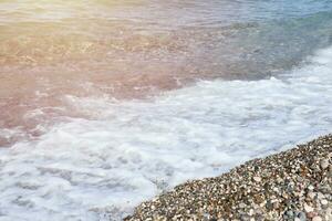 Bank of pebbles with the sea and beach in the background photo