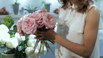 Woman takes a bouquet of pink roses at flower shop video