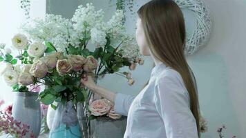 Female florist arranges flowers in vases at flower shop video