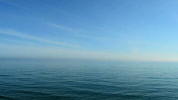 Blue calm sea at sunset with skyline and sky with few clouds video