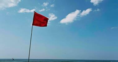 red flag on beach on sea or ocean as symbol of danger. The sea state is considered dangerous and swimming is prohibited. video