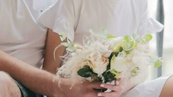 Closeup of newlyweds' hands and a bouquet of flowers.Male hands transfer a delicate white bouquet of roses to female hands video