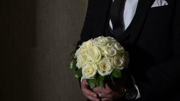 a man in a suit holding a bouquet of white roses video