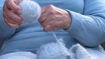 Hands of an old woman with a ball of woolen thread. Woman with knitting in her hands. Handicraft process close up. video