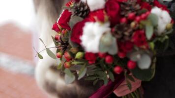 Close up of a bride holding a wedding bouquet with red roses. Bride holding flowers video