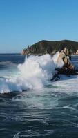 aéreo ver de movimiento olas estrellarse en contra rocas del océano poder olas implacablemente reunirse rocas danza de naturaleza. olas y rocas símbolos de salvaje intacto belleza oceánico podría escénico seducir. video